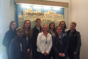 Members of the Youth Advisory Board pose with $30 million at the Federal Reserve.