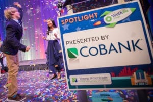Confetti fills the air with a sign displaying the Spotlight on YouthBiz Stars Logo and Presented by CoBank Logo