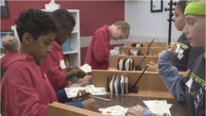 Students standing together writing checks in Young AmeriTowne Bank