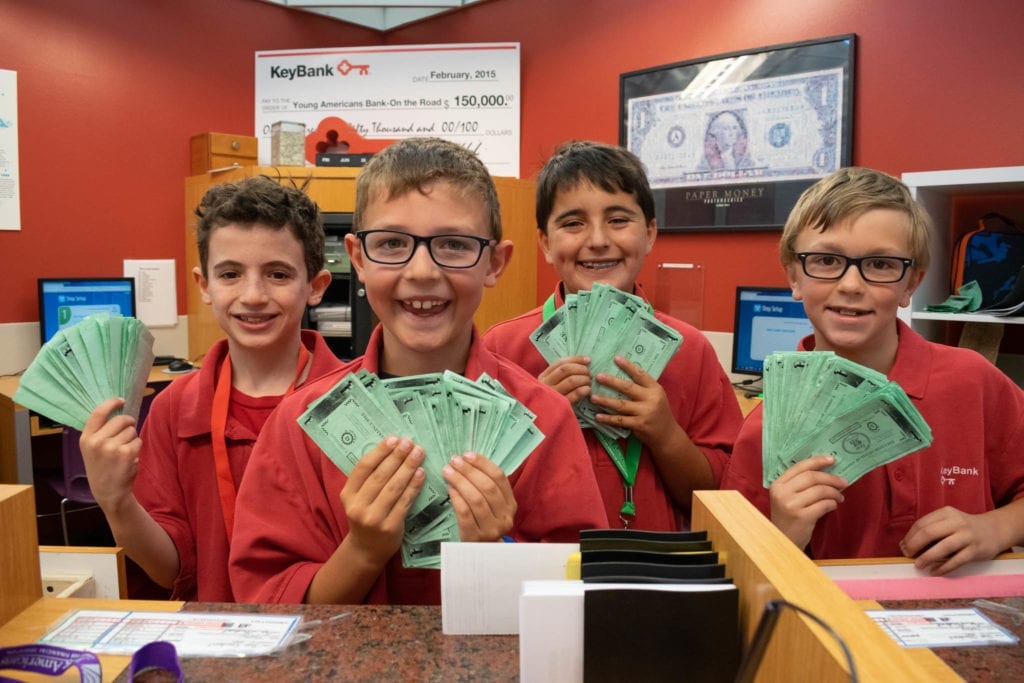 Summer Camp Bankers in Young AmeriTowne are shown holding cash
