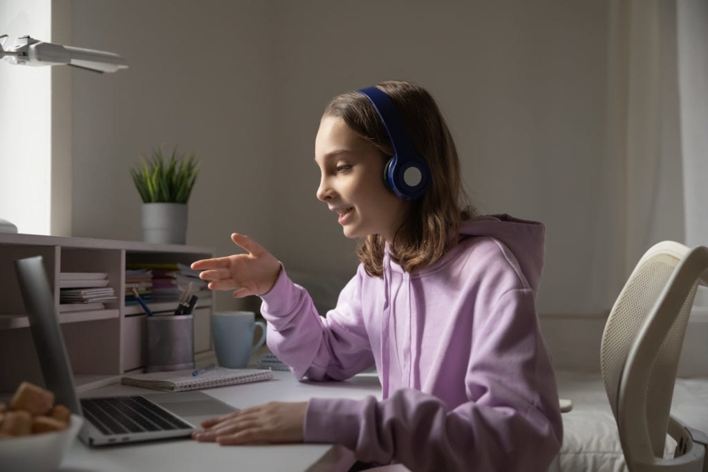 Teen girl studying online wearing headphones