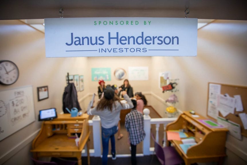 Janus Henderson Investor Sign displayed in Young AmeriTowne with Participants Inside