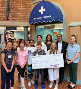 Young AmeriTowne participants smiling and holding a large check from Children's Hospital of Colorado