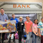 Alpine Bank Representative poses with several students while presenting a check for $100,000