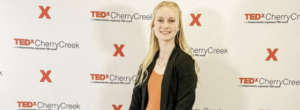 Anna Brekken poses in front of the TEDx-CherryCreek banner